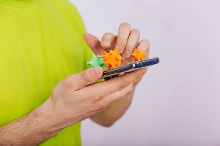 A guy in a green T-shirt is holding a smartphone with a coronavirus on the screen. Dirty phone.の写真素材