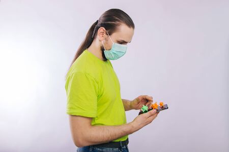 A guy in a green T-shirt is holding a smartphone with a coronavirus on the screen. Dirty phone.の写真素材