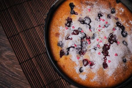 Berry pie sprinkled with icing sugar and pink sweet hearts.の写真素材