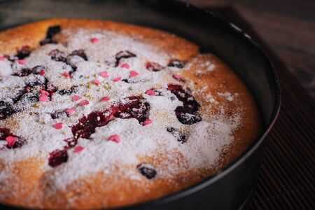 Berry pie sprinkled with icing sugar and pink sweet hearts.の写真素材