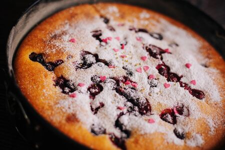 Berry pie sprinkled with icing sugar and pink sweet hearts.の写真素材