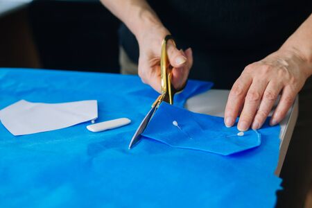 Creating handmade medical masks. Sewing protective masks at home. Cut on the table. The work of a...