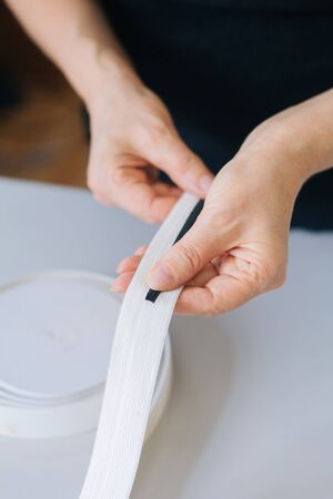 Close-up hands cut with scissors a wide elastic band on thin ribbons.の写真素材