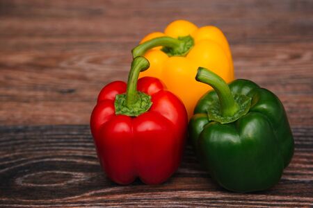 Sweet pepper multicolored on a dark wooden background. Red, yellow and green peppers are on the table.の写真素材