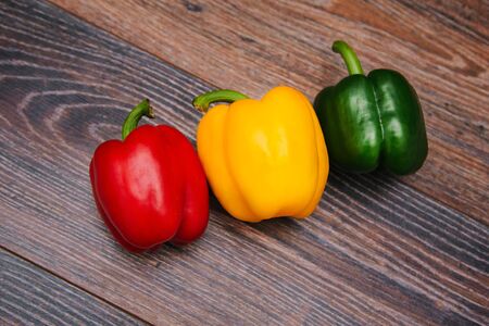 Sweet pepper multicolored on a dark wooden background. Red, yellow and green peppers are on the table.の写真素材