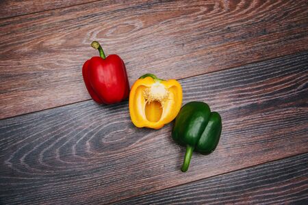 Sweet pepper multicolored on a dark wooden background. Red, yellow and green peppers are on the table.の写真素材