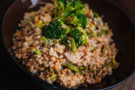 Ready buckwheat in a dark cup with vegetables. Broccoli and young beans in buckwheat.の写真素材