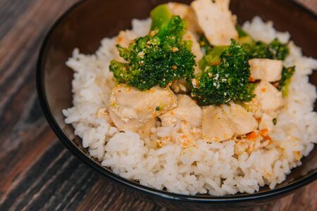 Green cabbage broccoli with rice and white meat. On a dark wooden table.の写真素材