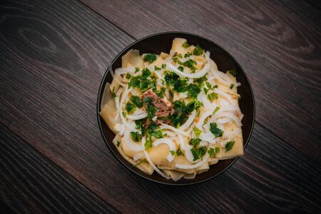 Beshbarmak in a dark plate, on a light wooden table. Dish of pastry with meat.の写真素材