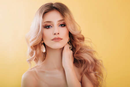 Beautiful, young model blonde close-up portrait. Girl with professional makeup and hairstyle, studio...