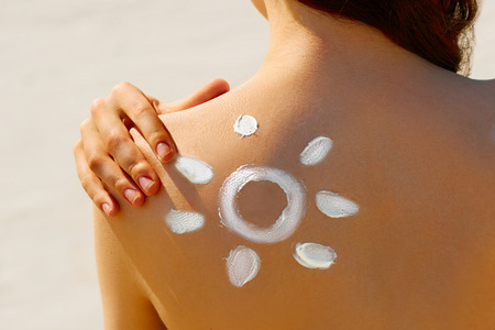 Portrait of gorgeous woman in bikini with the drawn sun on a shoulder at beachの写真素材