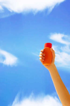 Close up of a female hand holding sun cream bottle.