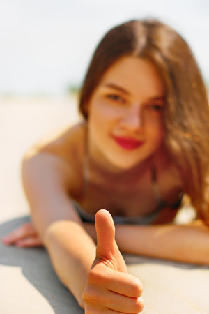 Beautiful  woman showing OK by her finger on the beachの写真素材