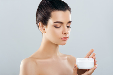 Beauty Concept. woman holds a moisturizer in her hand and spreads it on her face  to moisturize her skin and wrinkle from impurities. body care, skincare.Taking good care of her skinの写真素材