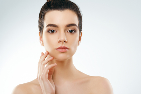 Beauty and Spa Concept. Beautiful Young Woman with Clean Fresh Skin touch own face.Facial treatment. Girl Female  With Natural Makeup.Cosmetology.の写真素材