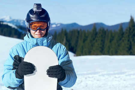 Snowboarder with action camera on a helmet. Close up Portrait of snowboarder in Carpathian Mountains, Bukovel Snowboarder. A mountain range reflected in the ski mask. wearing ski glasses in the mountainsの写真素材