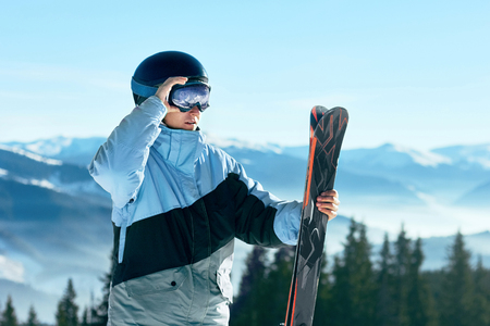 Portrait of a skier in the ski resort on the background of mountains and blue sky, Bukovel.  Ski goggles of a man wearing ski glasses. Winter Sportsの写真素材