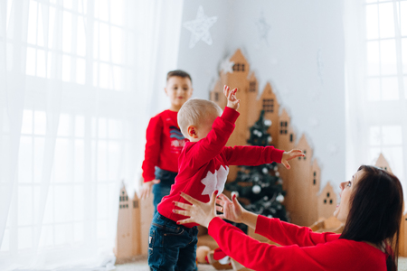Happy Little Boy Playing  with Christmas Toys Near Christmas Tree.  New Year Celebration. Decorations.   A little boy goes to his mother armsの写真素材