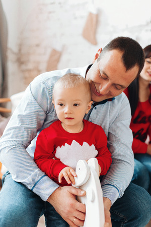 Happy Father With Child, Holding Christmas Gift and Smiling at Camera Near Christmas tree. New Year Celebration. Family decorates a Christmas treeの写真素材