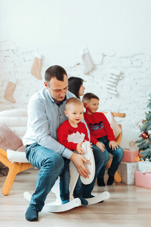Happy Father With Child, Holding Christmas Gift and Smiling at Camera Near Christmas tree. New Year Celebration. Family decorates a Christmas treeの写真素材
