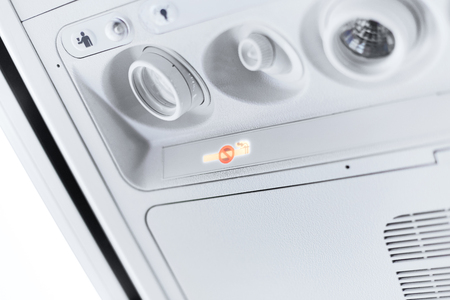 Reading light, air conditioner control and signage panel on the aircraft saying smoking is not allow, fasten the seat belt, air crew in need as well as the seat number.の写真素材