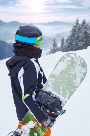 Female snowboarder  standing with snowboard in one hand and enjoying alpine mountain landscape - snowboarding conceptの写真素材