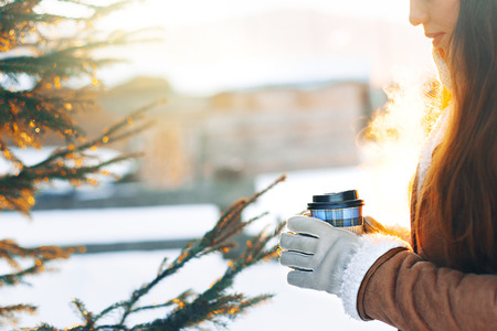 Beautiful Woman Going To With Coffee Walking in Winter. Portrait Of  Woman Holding Cup Of Hot Drink In Hand. Coffee to go. Sun rays.の写真素材