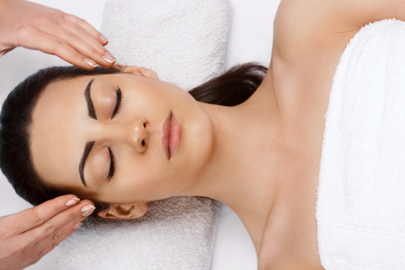 Face massage.  Close-up of young woman getting spa massage treatment at beauty spa salon.Spa skin and body care. Facial beauty treatment.Cosmetology.の写真素材