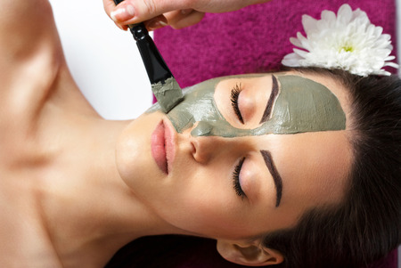 Woman with clay facial mask   in beauty spa. Skincare. Beauty Concept. Close-up portrait of beautiful girl applying facial mask.Facial treatment. Cosmetology. Body care girlの写真素材