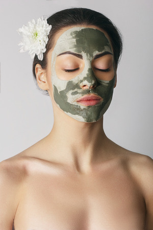 Beauty Spa Woman with perfect skin Portrait. Beautiful Brunette Spa Girl showing empty copy space on the open hand palm for text. Proposing a product. Gestures for advertisementの写真素材