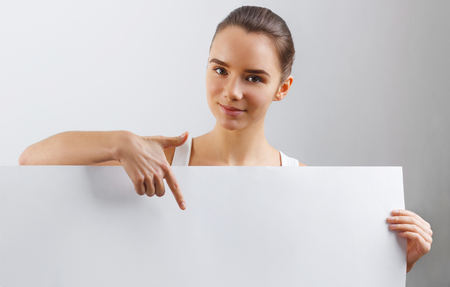 Portrait of happy smiling young woman, showing empty blank signboard with copyspace. Business Woman holding a big white bannerの写真素材