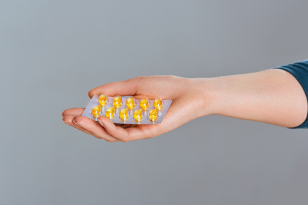 Vitamins And Dietary Supplements. Woman Holding  Vitamin Pill In Hand. Closeup Of Happy Girl Taking Medication. Healthy Diet Nutrition Concept. Image tablet of activated charcoal in female hands.の写真素材