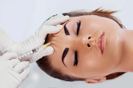 Beauty Procedure. Portrait Beautiful Young Woman Receiving Hyaluronic Acid Injection. Closeup Of Hands In Gloves Holding Syringe Near Attractive Female Face. Facial Beauty Injections. Faceliftの写真素材