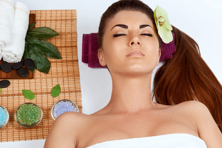 Young  girl with thick eyebrows and perfect skin at white background, towel on head, beauty photo concept, skin care, spa concept, treatment, facial massage.の写真素材