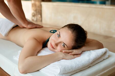 Beautiful young woman receiving massage in spa salon. Body care. Spa body massage woman hands treatment.の写真素材