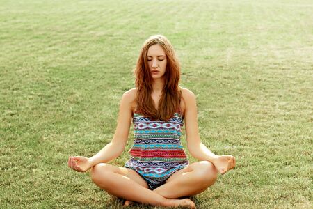 woman practices yoga and meditates in the lotus position on the beachの写真素材