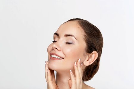 Beautiful woman portrait, skin care concept, beautiful skin. Portrait of female hands with manicure nails. Girl cosmetics. Facial treatment.の写真素材