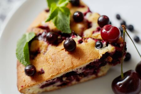 Piece of pie with blueberries, rasberry,cherries and mint for dessert on a white plate, napkin. Pieces of delicious homemade cakeの写真素材