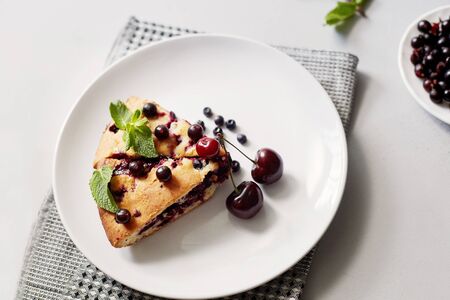 Piece of pie with blueberries, rasberry,cherries and mint for dessert on a white plate, napkin. Pieces of delicious homemade cakeの写真素材