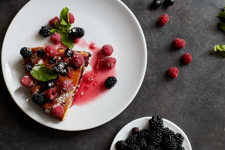 Piece of pie with blueberries, rasberry and mint for dessert on a white plate, napkin. Pieces of delicious homemade cake on a backgroundの写真素材