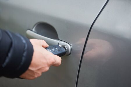 Man with car key. Opening car door.