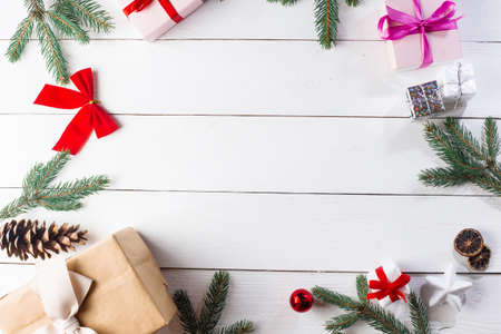 Beautiful Christmas composition on wooden white background with Christmas gift boxes, snowy fir branches, conifer cones, cinnamon dried fruits, holiday decoration, caramel stick. New Year. Top view, copy space.の写真素材