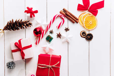 Beautiful Christmas composition on wooden white background with Christmas gift boxes, snowy fir branches, conifer cones, cinnamon dried fruits, holiday decoration, caramel stick. New Year. Top view, copy space.の写真素材
