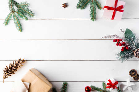 Beautiful Christmas composition on wooden white background with Christmas gift boxes, snowy fir branches, conifer cones, cinnamon dried fruits, holiday decoration, caramel stick. New Year. Top view, copy space.の写真素材
