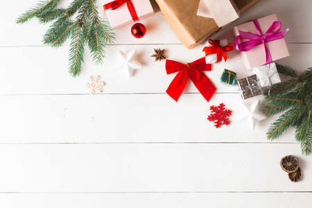 Beautiful Christmas composition on wooden white background with Christmas gift boxes, snowy fir branches, conifer cones, cinnamon dried fruits, holiday decoration, caramel stick. New Year. Top view, copy space.の写真素材