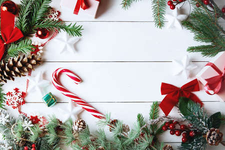 Beautiful Christmas composition on white background with Christmas gift boxes, snowy fir branches, conifer cones, holiday decoration, caramel stick and red berry. Top view, copy space.の写真素材