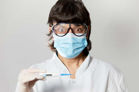 Doctor looking at thermometer. Female hands holding a digital thermometer. Girl measures the...