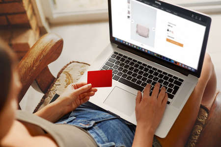 Hand holding credit card and using laptop. Businesswoman or entrepreneur working from home. Online shoppingの写真素材