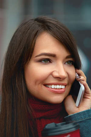 Beautiful young woman talking on phone and look straight ahead. Holding smartphoneの写真素材