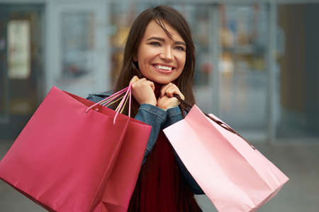 Happy woman holding shopping bags and smiling near the mallの写真素材